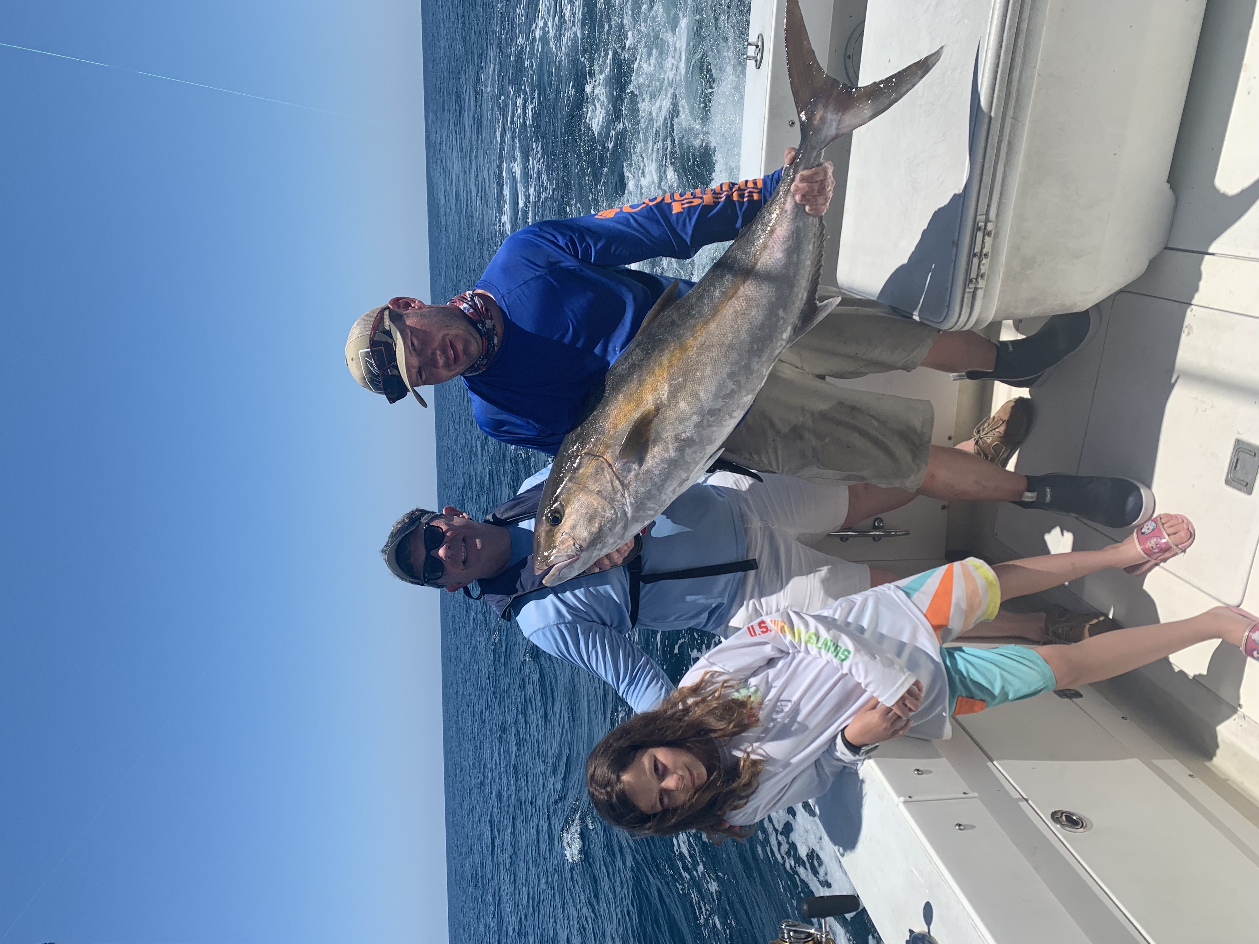 Group holding a large amberjack on the boat