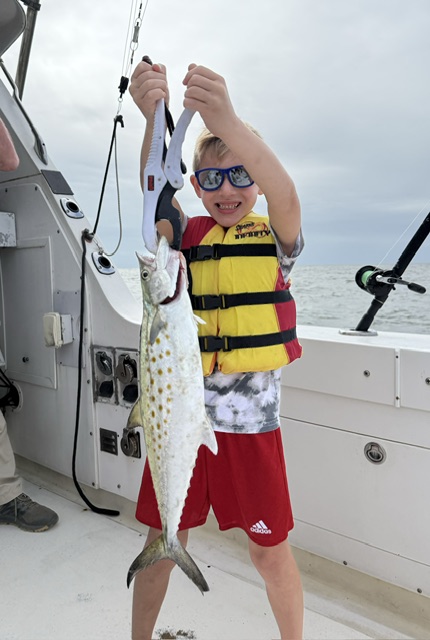 Kid holding a Spanish mackerel on the boat